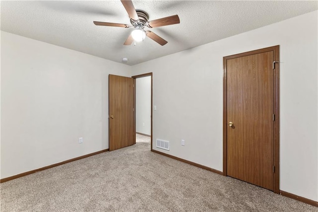 unfurnished bedroom featuring baseboards, visible vents, a textured ceiling, and carpet