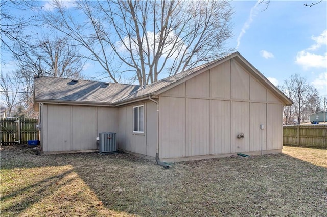 view of home's exterior featuring central air condition unit, a lawn, a shingled roof, and fence