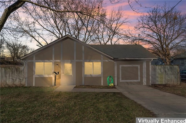 view of front of home with a shingled roof, stucco siding, a lawn, and fence