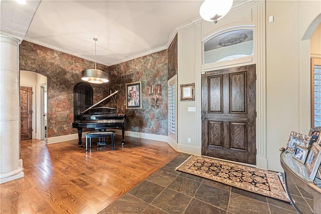 foyer featuring crown molding, baseboards, wood finished floors, arched walkways, and ornate columns