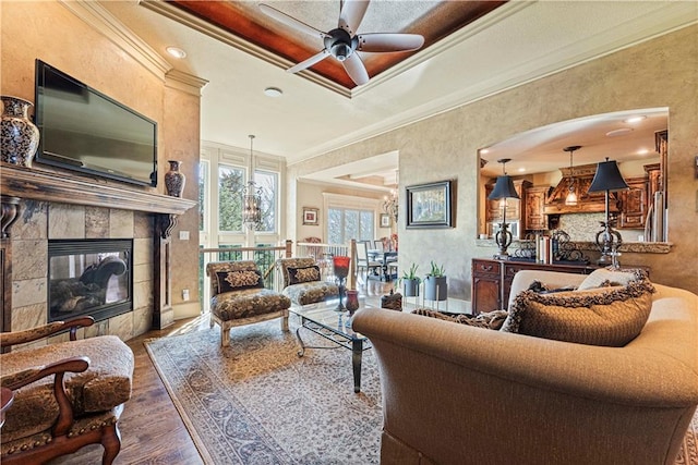 living room with a fireplace, crown molding, wood finished floors, and ceiling fan