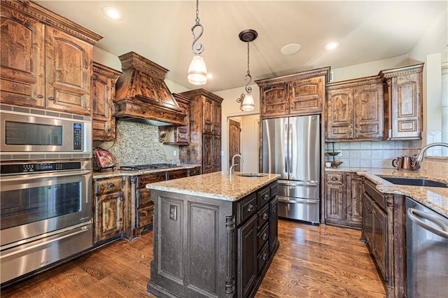 kitchen with appliances with stainless steel finishes, dark wood-type flooring, custom range hood, and a sink