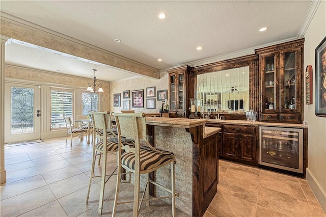 bar with crown molding, beverage cooler, an inviting chandelier, hanging light fixtures, and a textured ceiling