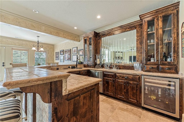 kitchen with a breakfast bar area, beverage cooler, a peninsula, dark brown cabinetry, and crown molding