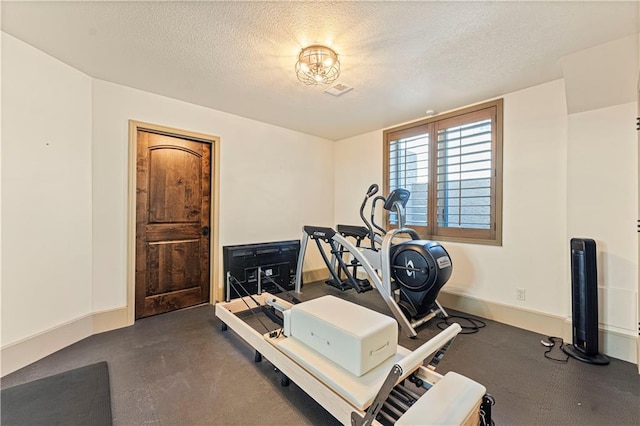 exercise room with baseboards and a textured ceiling