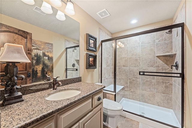 bathroom with vanity, a shower stall, toilet, and visible vents