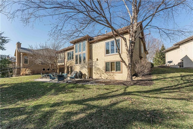 rear view of house featuring a patio, a yard, and stucco siding