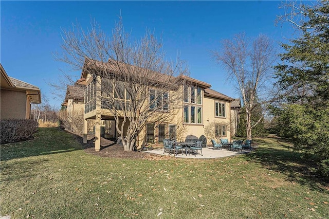 back of property with a patio, a yard, and stucco siding