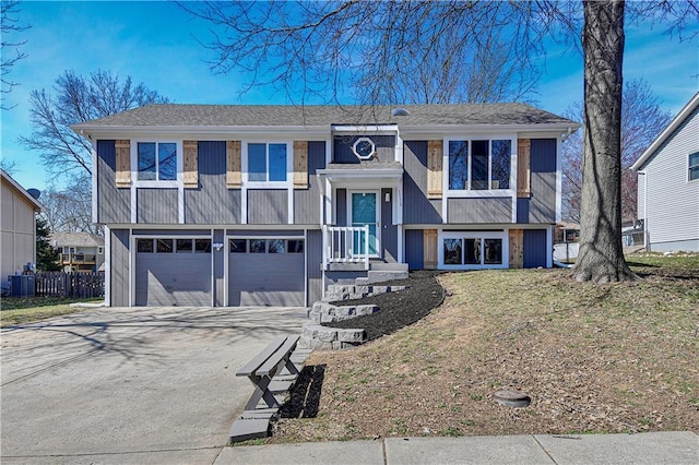 split foyer home with central AC, concrete driveway, an attached garage, and fence