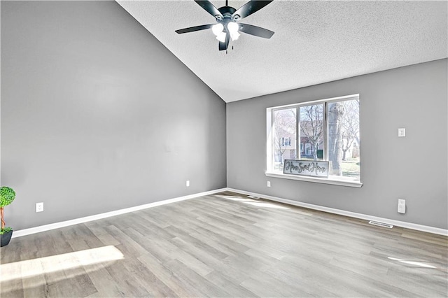 empty room featuring wood finished floors, a ceiling fan, baseboards, and lofted ceiling