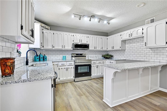 kitchen with white cabinetry, light wood finished floors, appliances with stainless steel finishes, and a sink