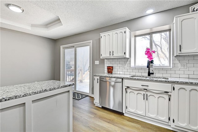 kitchen featuring a sink, light wood-style floors, white cabinets, a raised ceiling, and dishwasher