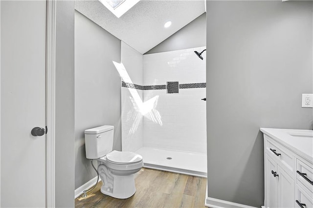 bathroom featuring a textured ceiling, lofted ceiling with skylight, toilet, and tiled shower