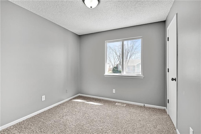 spare room with baseboards, visible vents, carpet floors, and a textured ceiling