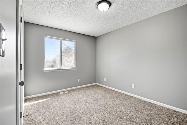 empty room featuring carpet flooring, a textured ceiling, and baseboards