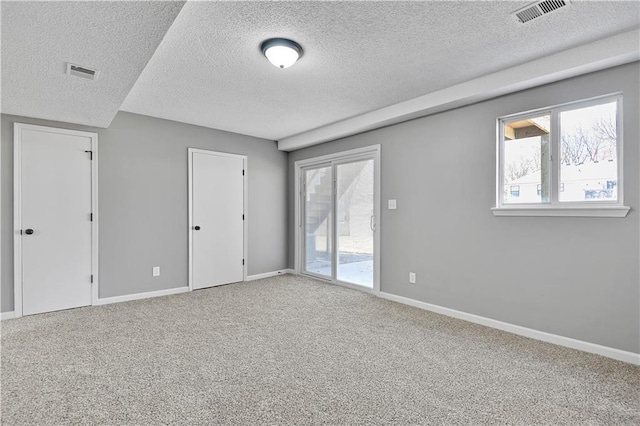 carpeted spare room featuring visible vents, baseboards, and a textured ceiling