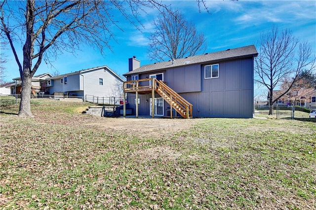 rear view of house featuring fence, stairs, a chimney, a yard, and a deck