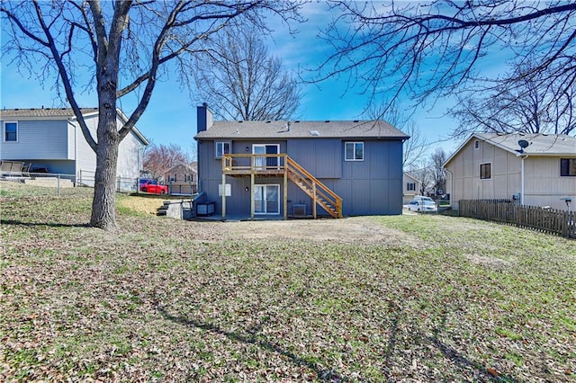 rear view of property with stairway, fence, a wooden deck, a chimney, and a lawn