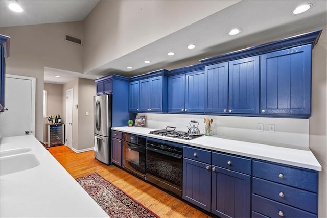 kitchen with beverage cooler, visible vents, stainless steel appliances, and blue cabinets