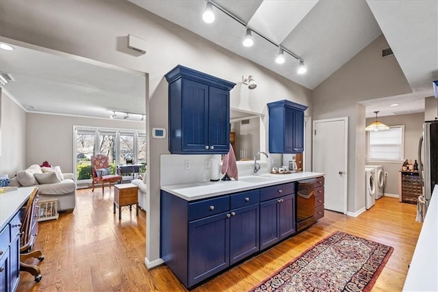 kitchen with blue cabinetry, washing machine and dryer, open floor plan, and a sink