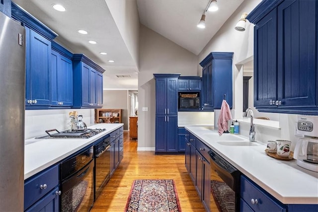 kitchen featuring light wood finished floors, blue cabinetry, light countertops, black appliances, and a sink