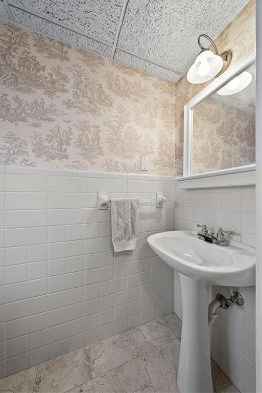 bathroom with wainscoting and wallpapered walls