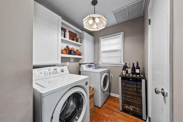 laundry area featuring visible vents, light wood-type flooring, wine cooler, a dry bar, and independent washer and dryer