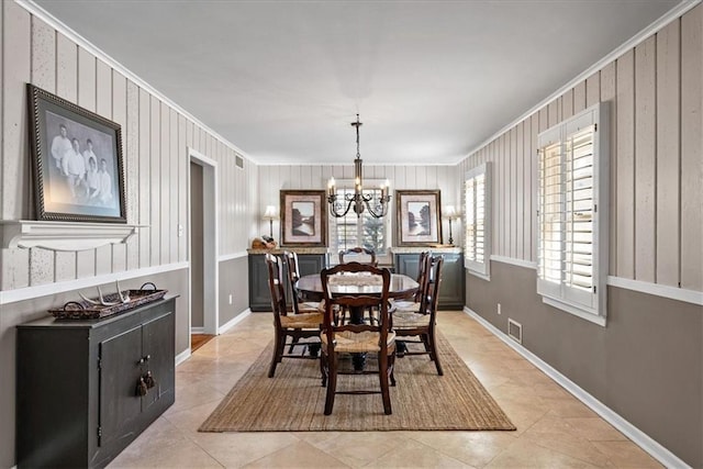 dining space featuring light tile patterned floors, baseboards, visible vents, ornamental molding, and a chandelier