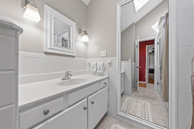 bathroom with vanity, tile walls, tile patterned floors, and wainscoting