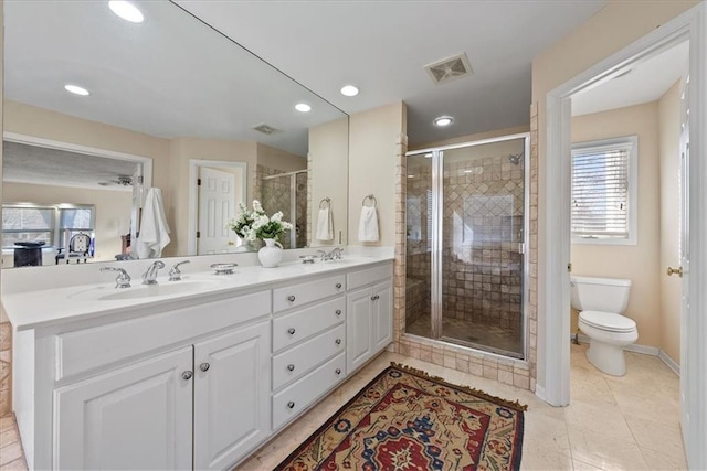 bathroom featuring visible vents, a shower stall, toilet, double vanity, and a sink