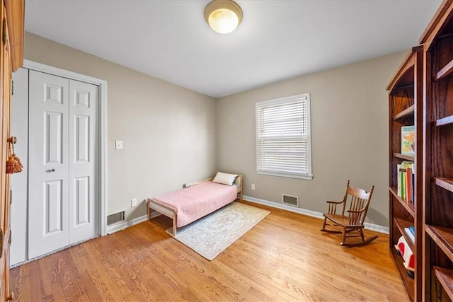 bedroom with visible vents, baseboards, a closet, and light wood finished floors