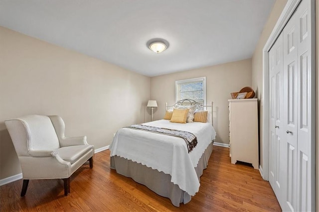 bedroom with a closet, baseboards, and light wood-style flooring