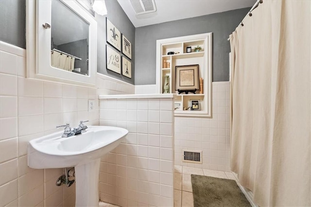 full bath with visible vents, wainscoting, tile walls, and a shower with curtain