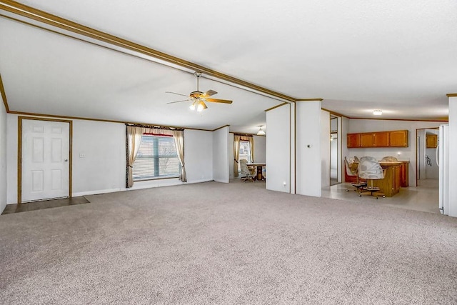 unfurnished living room featuring ceiling fan, ornamental molding, carpet flooring, and vaulted ceiling