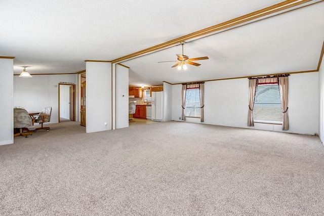 unfurnished living room featuring light colored carpet, vaulted ceiling with beams, ceiling fan, and crown molding