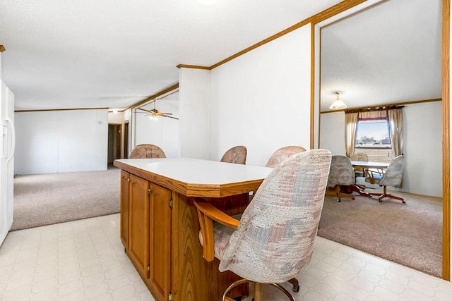 dining space featuring light colored carpet, light floors, a ceiling fan, and ornamental molding