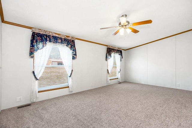 carpeted spare room featuring ornamental molding, visible vents, and ceiling fan