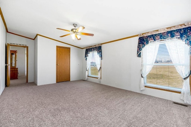 unfurnished bedroom featuring ceiling fan, carpet flooring, visible vents, and ornamental molding