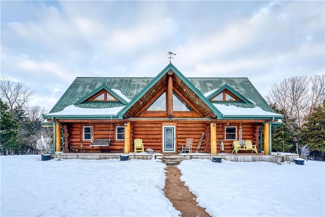 log cabin with a standing seam roof, log siding, covered porch, and metal roof