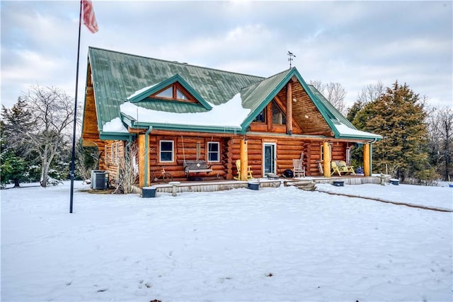 cabin with log siding, a porch, central AC, and metal roof