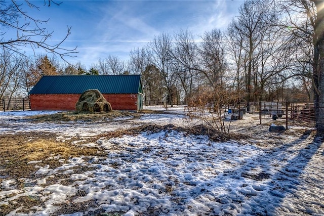 snowy yard featuring an outbuilding and fence