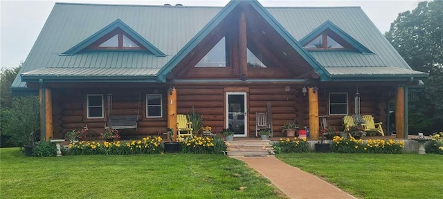 log home featuring a front lawn, log exterior, covered porch, and metal roof