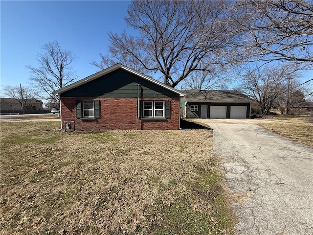 view of front of home with driveway, brick siding, an attached garage, and a front lawn