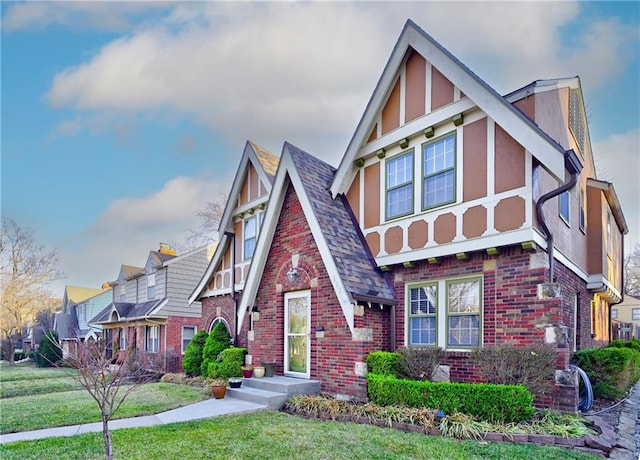 tudor home with a residential view, a shingled roof, stucco siding, a front lawn, and brick siding