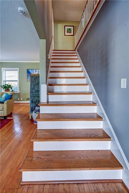 stairs with baseboards, a textured ceiling, and hardwood / wood-style flooring