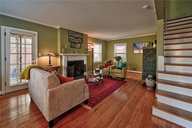 living room with ornamental molding, a fireplace, stairs, and hardwood / wood-style flooring