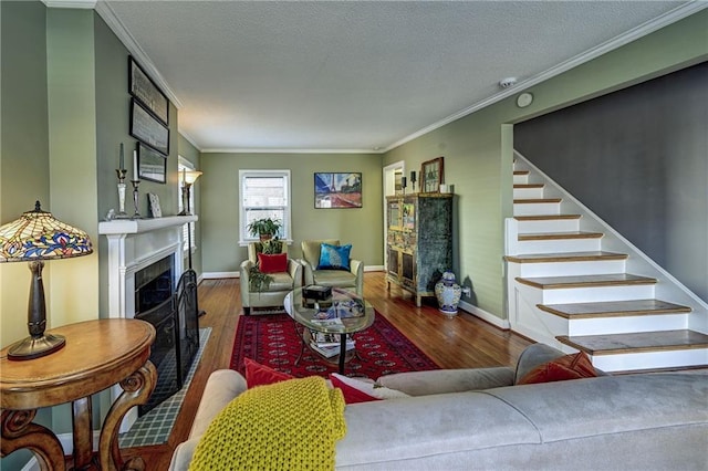 living room with stairs, wood finished floors, a fireplace, and ornamental molding