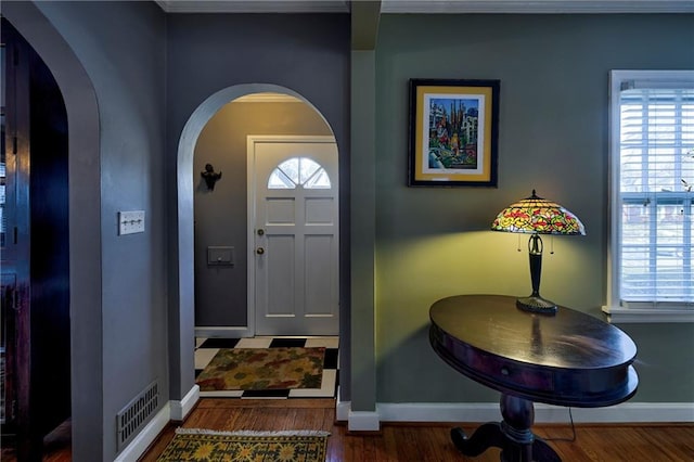 foyer with arched walkways, baseboards, and wood finished floors