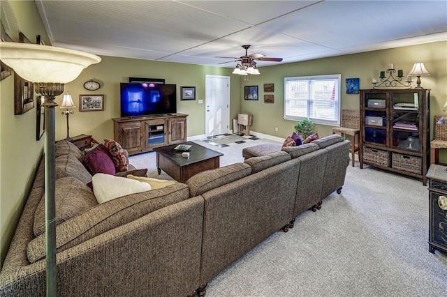 living room featuring light colored carpet, baseboards, and ceiling fan