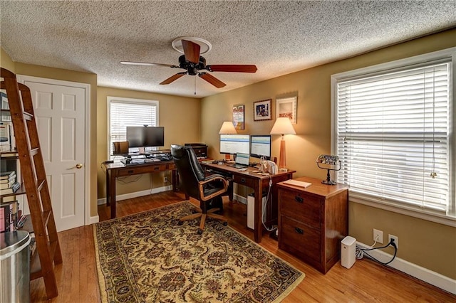 office area with a textured ceiling, wood finished floors, baseboards, and ceiling fan